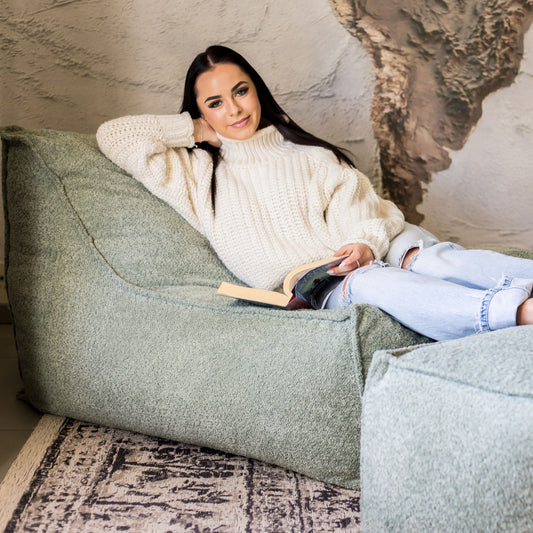 Woman relaxing on a daybed chair in sage boucle fabric