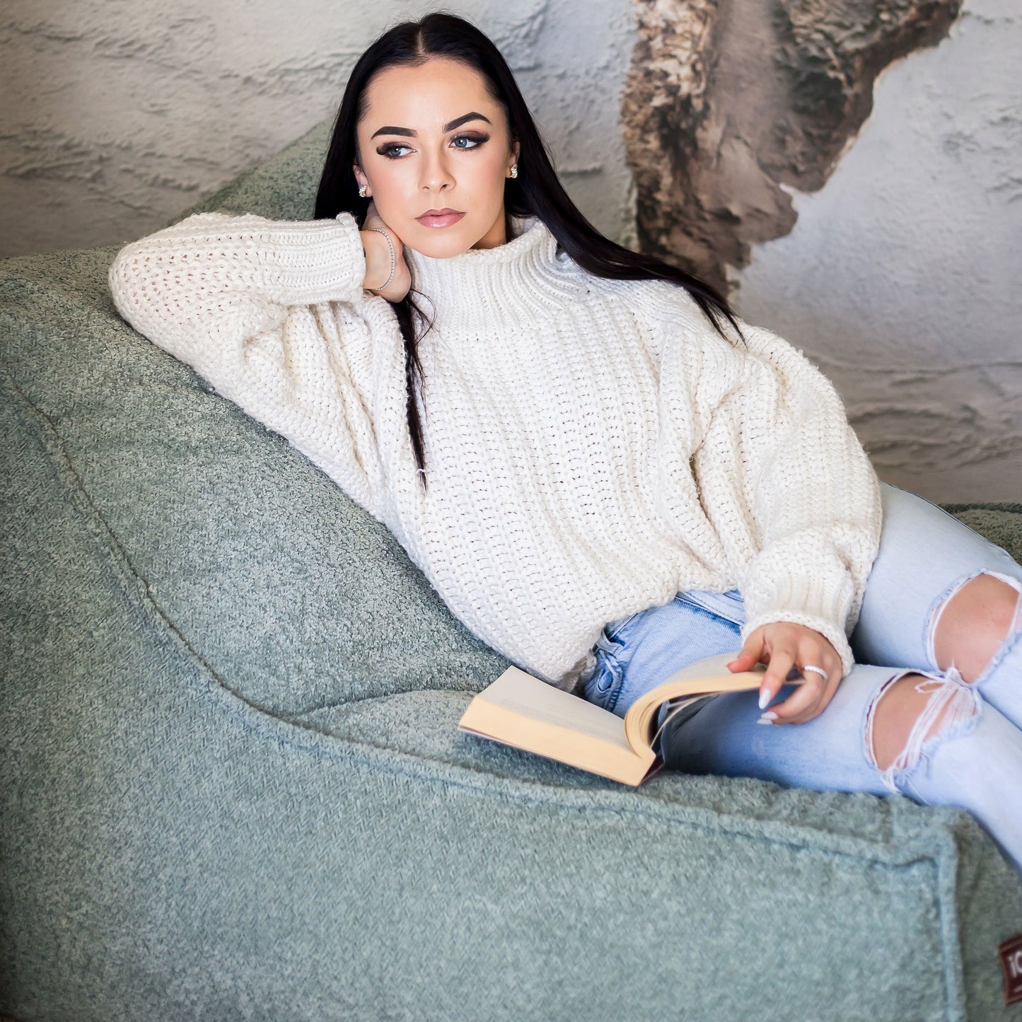 Woman read on a sage daybed chair 
