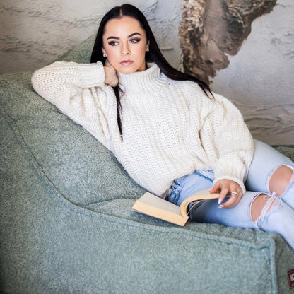 Woman read on a sage daybed chair 